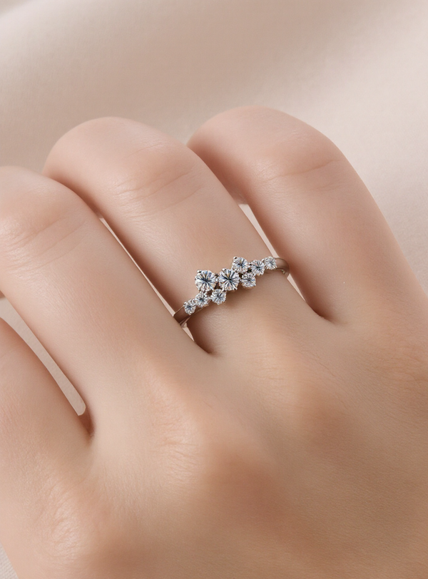 Silver ring with moissanites on a finger against a neutral background