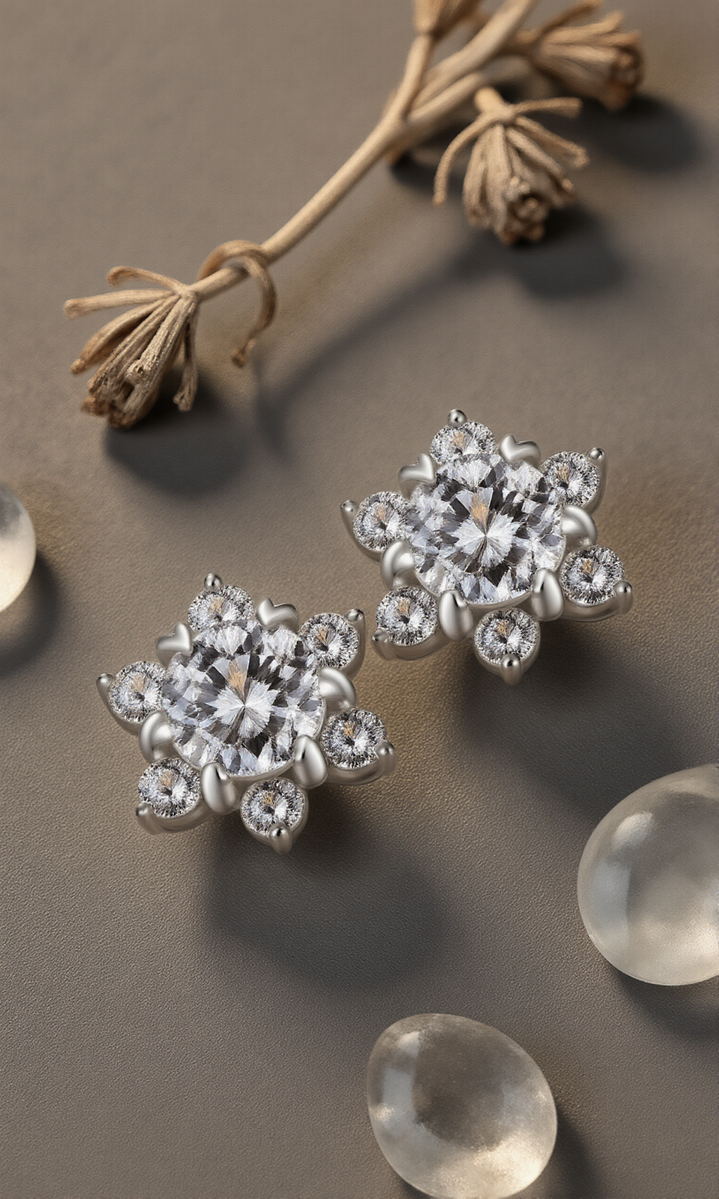 Silver floral earrings with clear stones on a gray surface with dried flowers and clear stones.