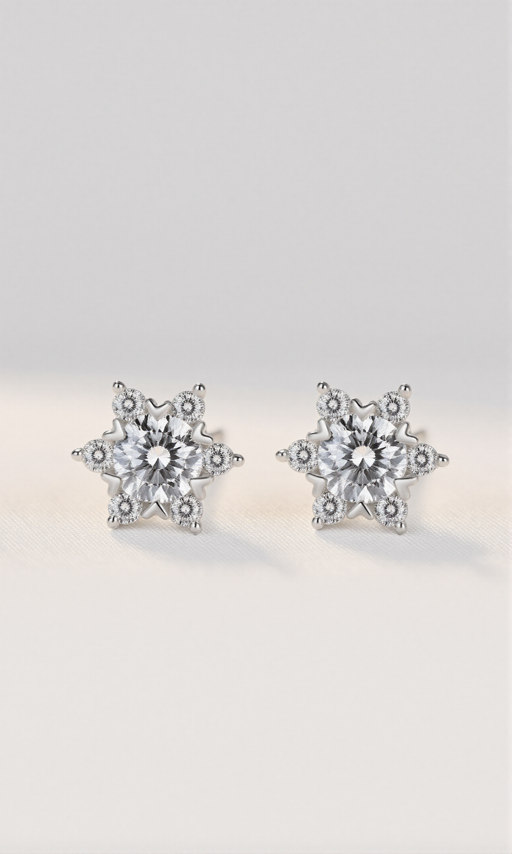 Star-shaped silver earrings with clear gemstones on a light gray background