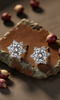 Star-shaped moissanite earrings on a rustic wooden surface with red fruits.