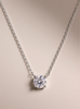 Silver necklace with a round moissanite pendant on a beige background