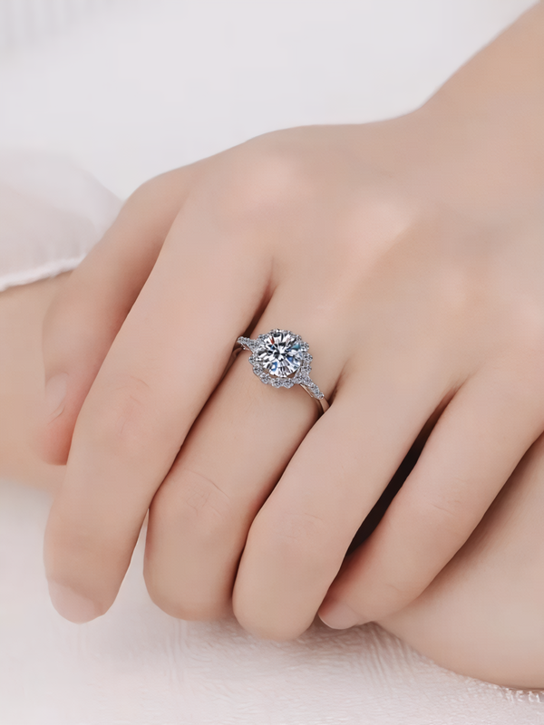 Close-up of a hand wearing a moissanite ring on a light background
