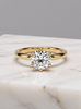 Gold ring with a large moissanite on a marble surface